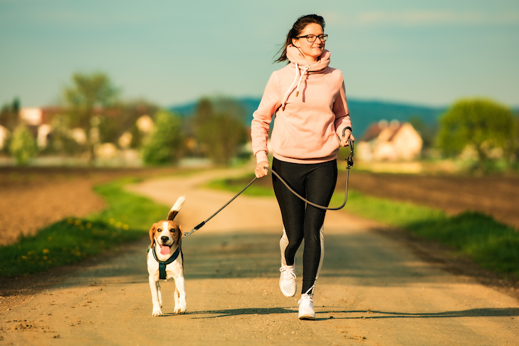 woman jogging on a path outdoors with a beagle